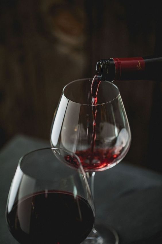 vin rouge servit dans un verre à vin sur fond sombre